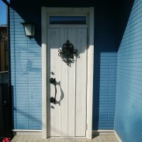 青い外壁に映える白い木目調のドア【LIXILリシェントD77型】東京都葛飾区
